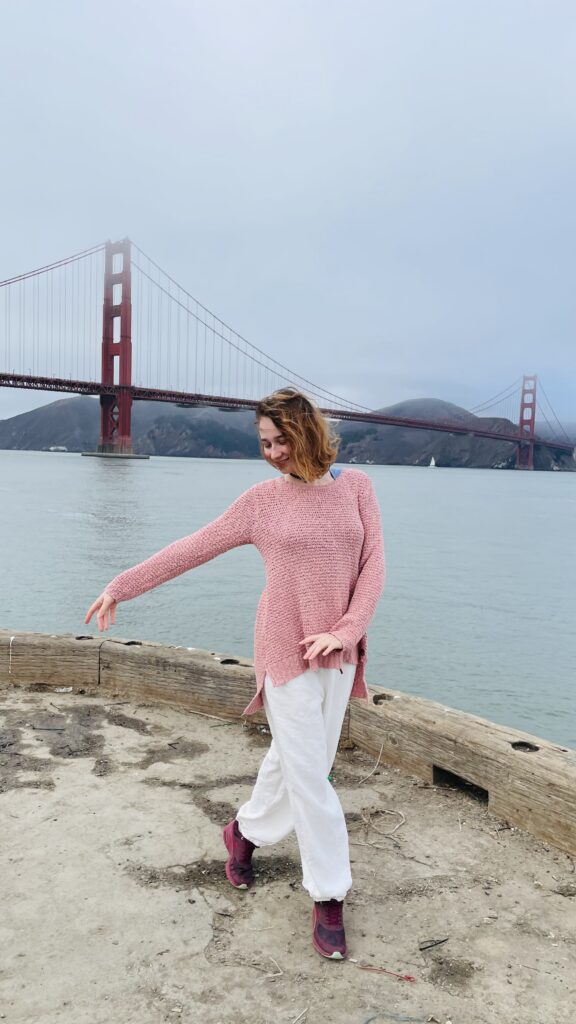 Girl dancing in front of golden gate bridge